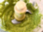 Blender with creamy green pesto sauce, textured and colorful, inside a food processor. The mood is fresh and appetizing.