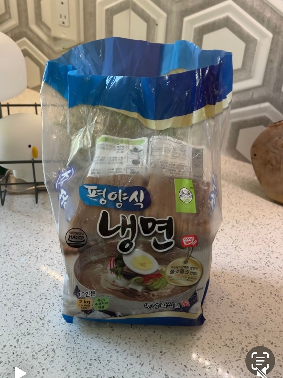 파란색 포장지의 냉면 팩이 탁자 위에 놓여 있다. 패키지에 삶은 계란과 국수 그림, '평양식 냉면' 글자가 보임.