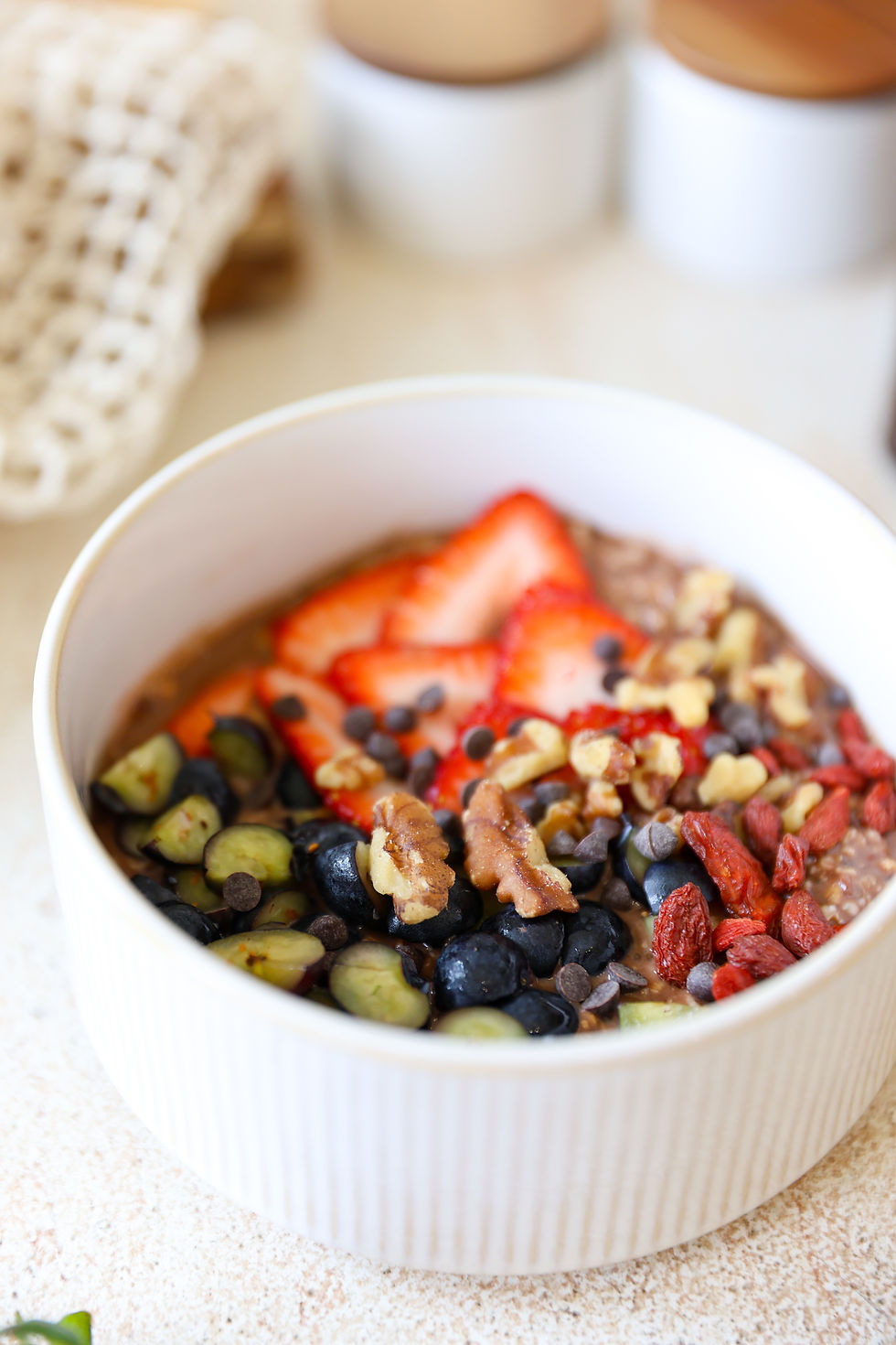 Chocolate overnight oats topped with strawberries, blueberries, walnuts, goji berries, and chocolate chips in a glass jar
