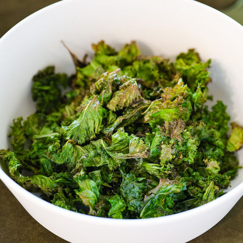 Homemade baked kale chips seasoned with sea salt and olive oil, served as a healthy crunchy snack for kids and families.