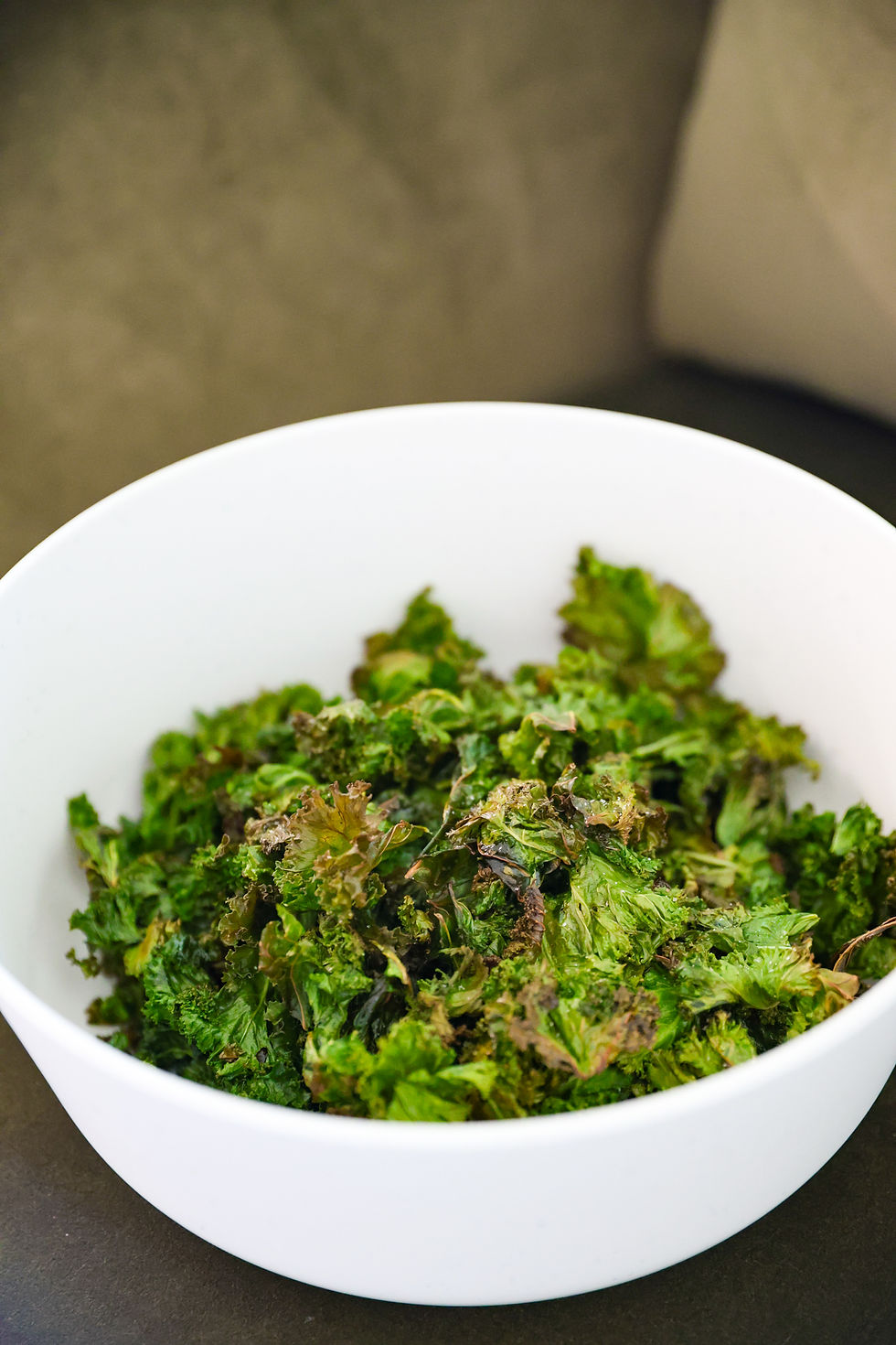 Homemade kale chips spread on a baking sheet ready to be baked until crispy.