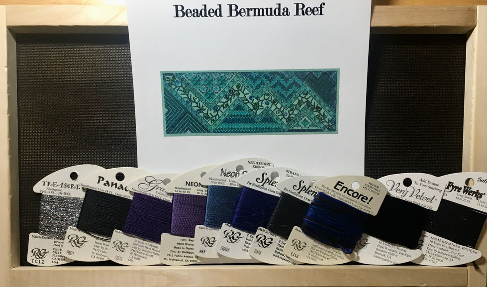 Photo of blank black canvas on working frame, also showing cover of chart for the piece and a lineup of the threads used in the piece.