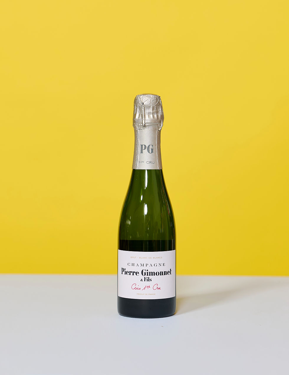 Pierre Gimonnet & Fils Champagne Cuis Premier in kleiner Flasche vor gelbem Hintergrund