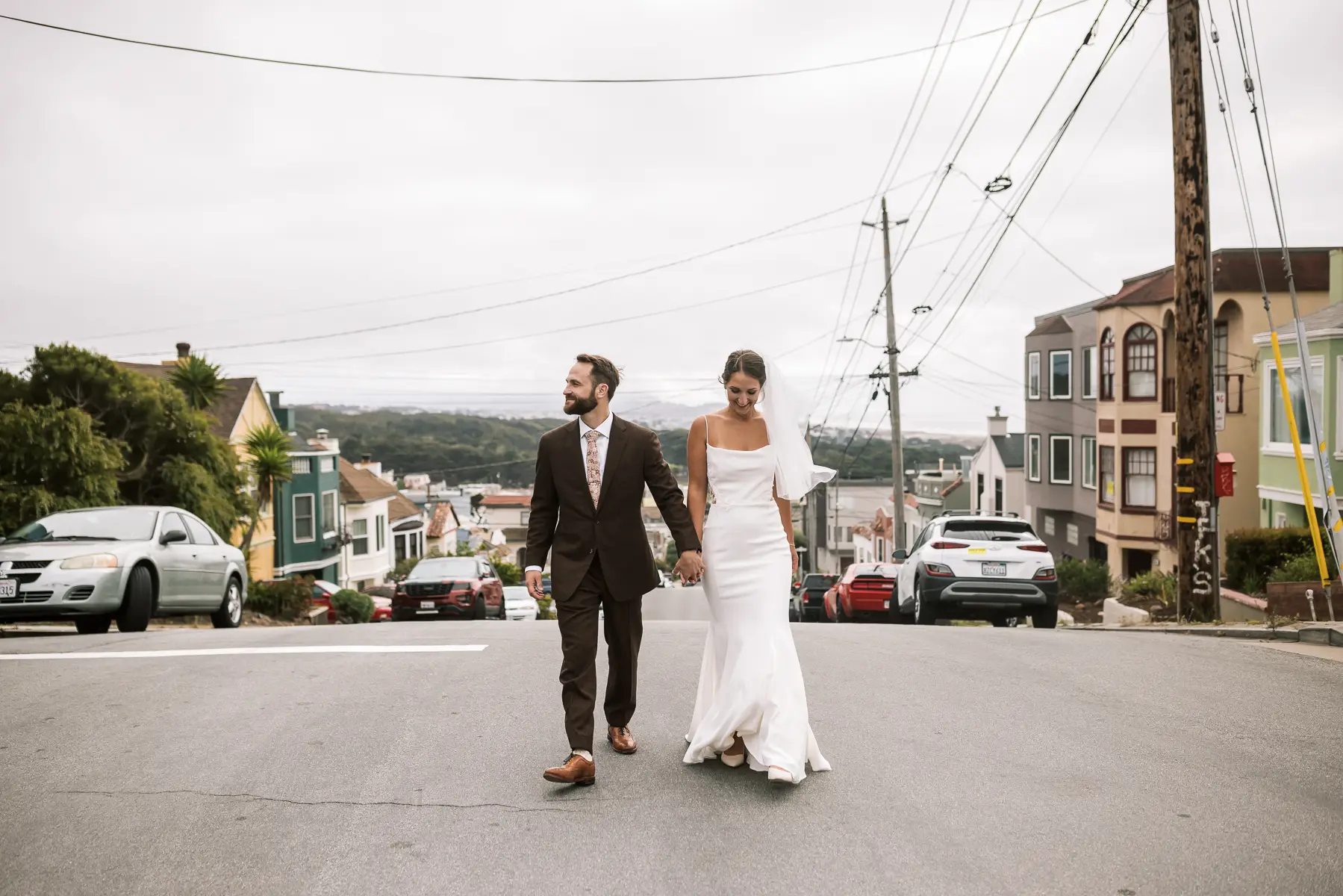 san francisco wedding couple walking through city street with hills and neighborhood homes in background