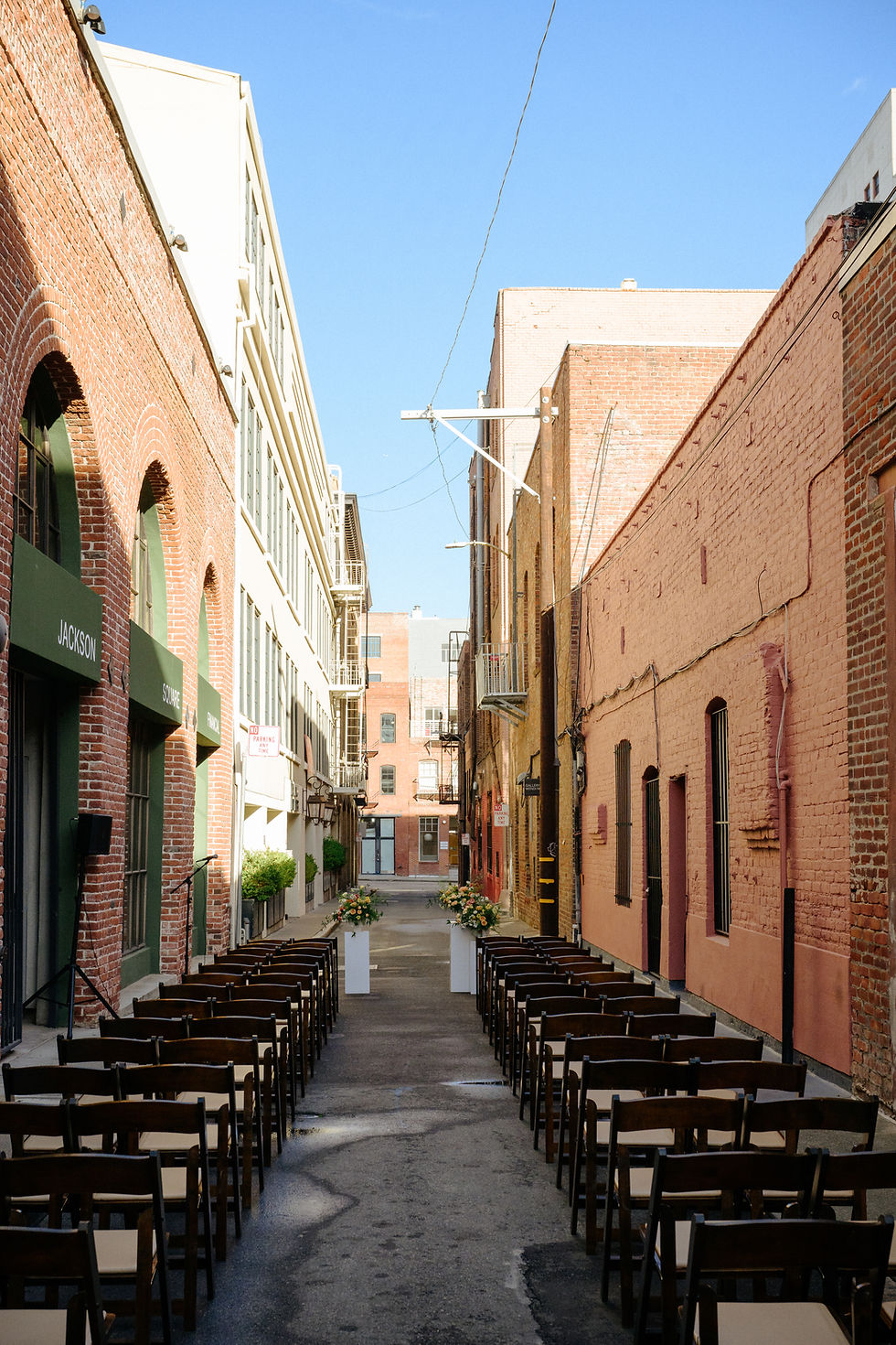 outdoor wedding ceremony setup in san francisco alley with chairs and floral arrangements between brick buildings