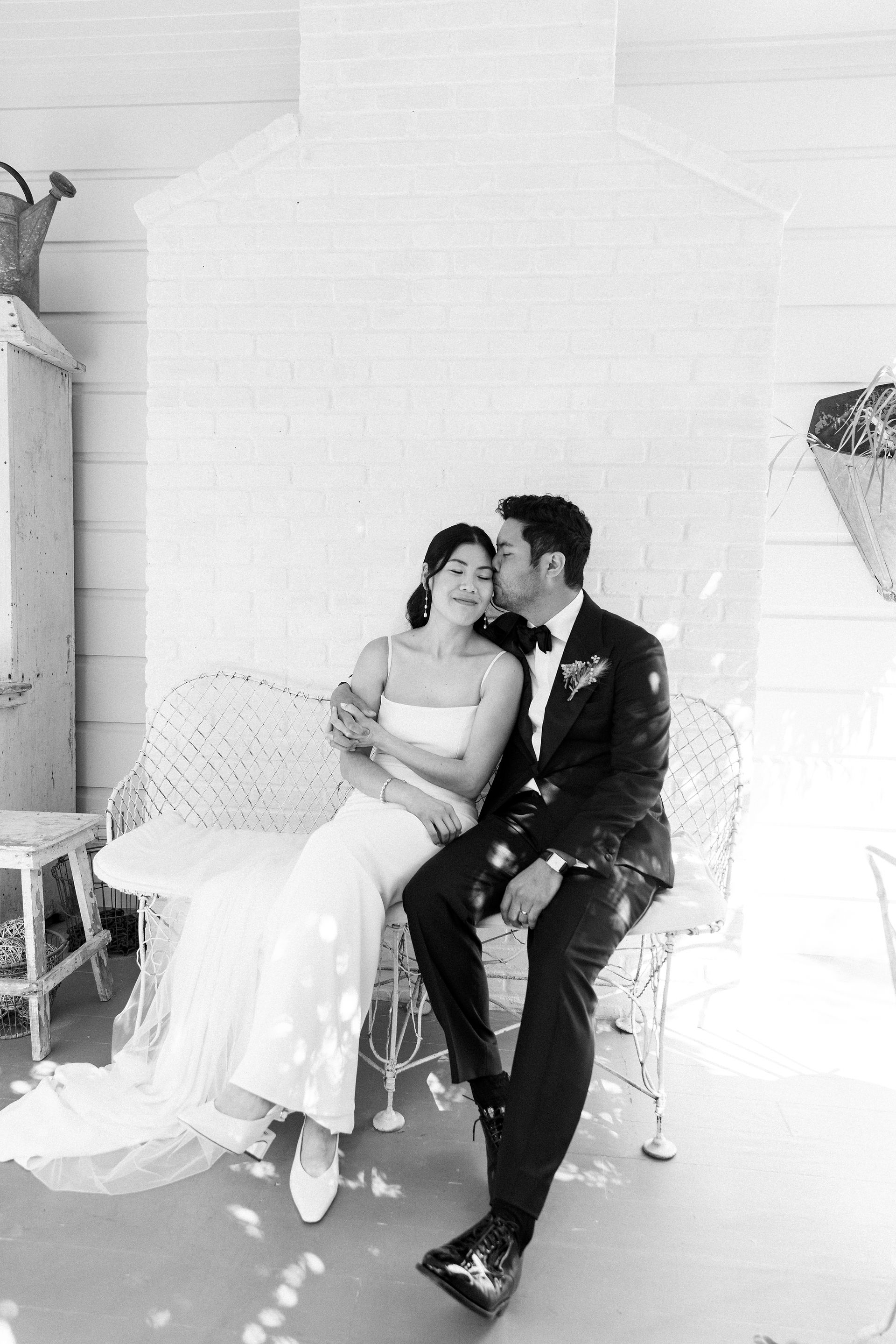 Black and white portrait of bride and groom sitting on porch at Olive Oaks wedding venue in Sebastopol, California.