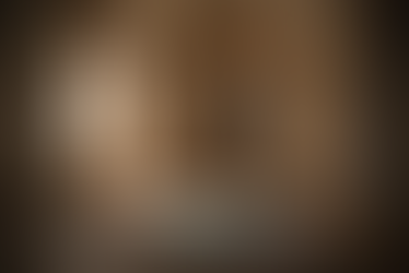 Empty interior room with arched walls, decorative tiled panels, a patterned rug on the floor, two cushions, ceramic vessels, and soft daylight entering from a side window.