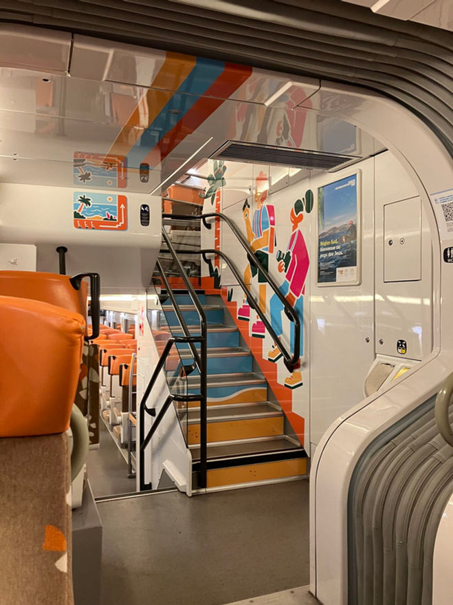 Vision de l'escalier habillé avec des stickers illustrant la plage, la mer et des touristes montant l'escalier.