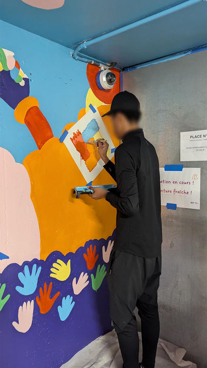 Un des jeunes en train de peindre son illustration de 4 mains se tenant ensemble représentant la solidarité