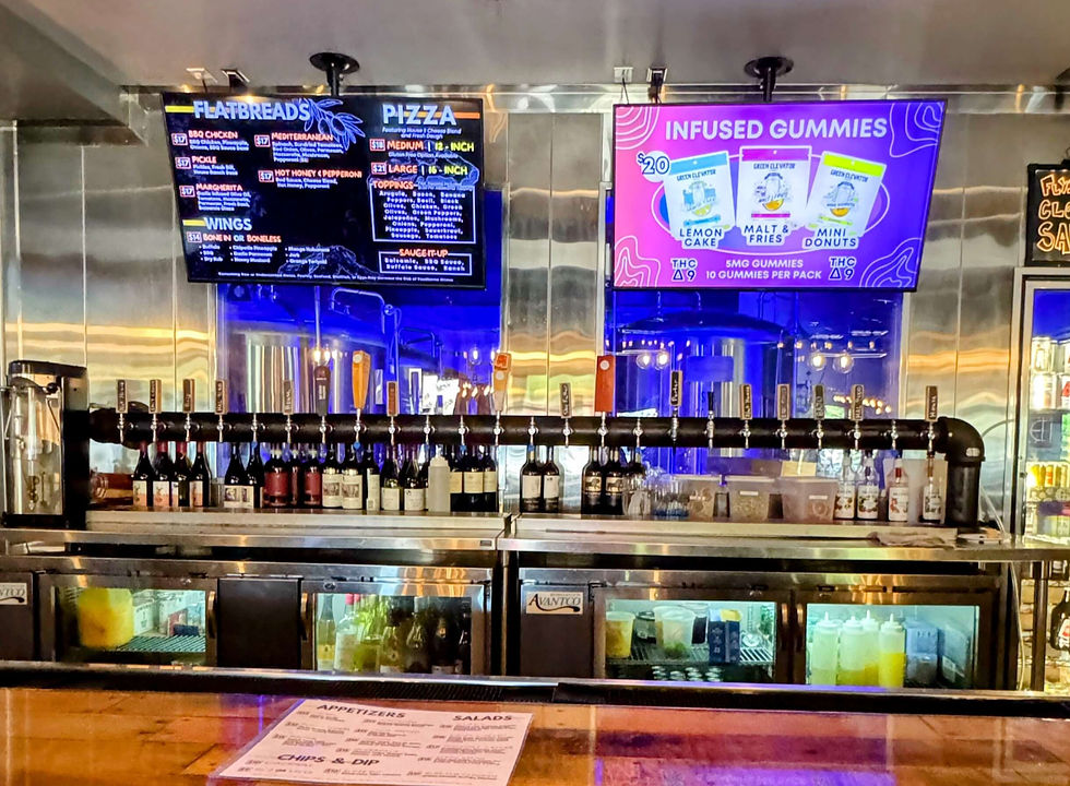 row of beer taps with two tv screens above them
