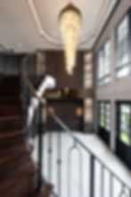Contemporary stair hall with luxury chandelier, iron railings, and modern interior architecture.