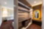 Luxury dressing room with custom wardrobes, illuminated shelving, vanity area, and premium built-in furniture.