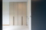 Minimalist floor-to-ceiling custom wardrobe with neutral finish and modern handles