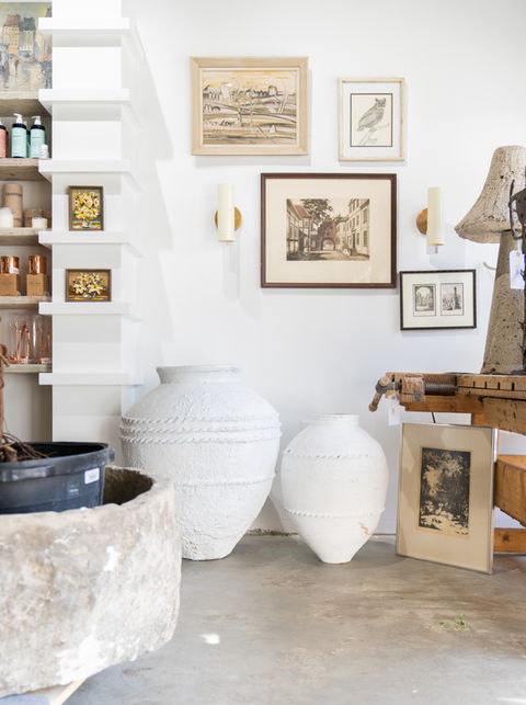 Large white pottery vases and framed art in a home boutique.