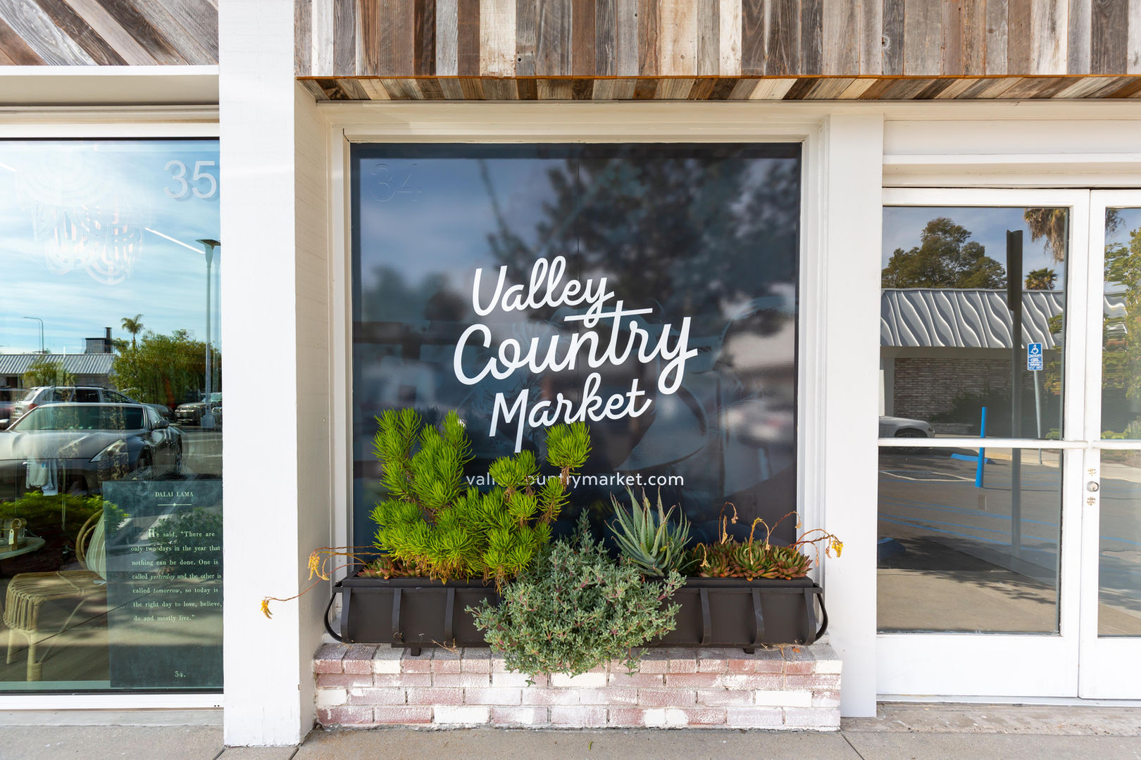 Valley Country Market storefront window with logo and plants