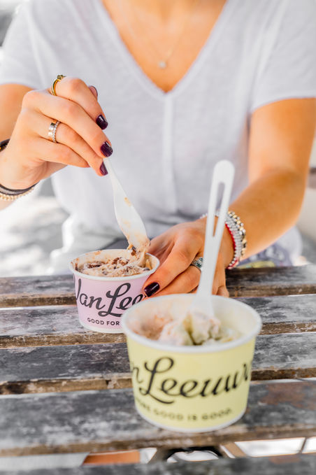 Woman eating Van Leeuwen ice cream at a wooden table