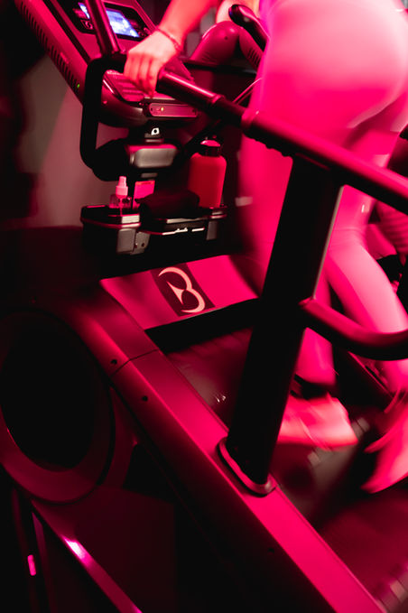 Person using a stair climber machine under red lighting