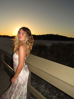Allison V standing outdoors at sunset on a wooden walkway