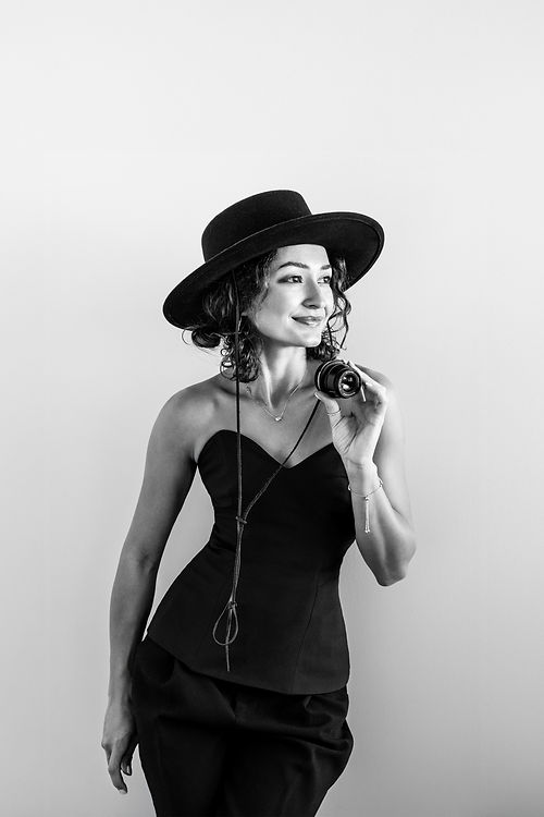 Toronto photographer Uli Goja laughing and holding a camera lens, showing her creative and joyful personality.