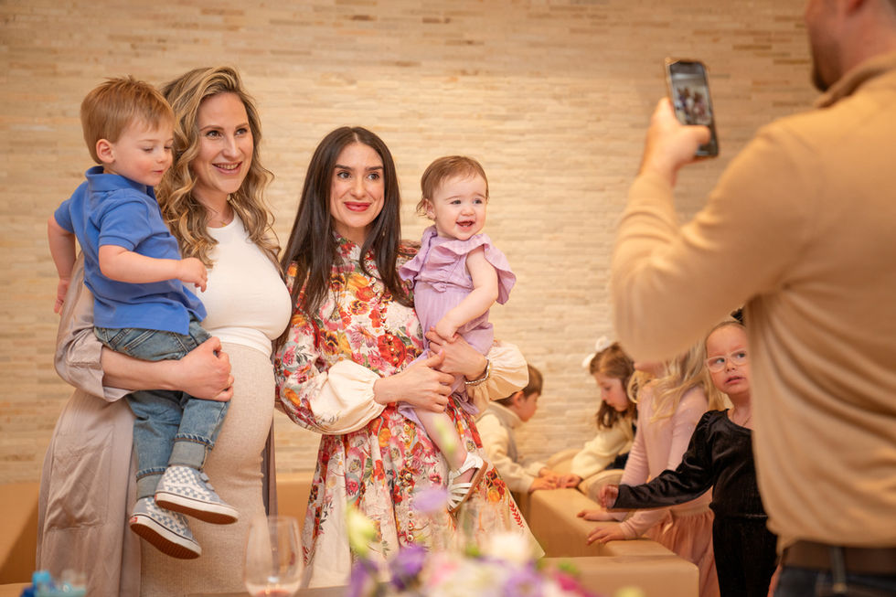 Guests taking photos with a baby and her mother during a first birthday celebration in Toronto
