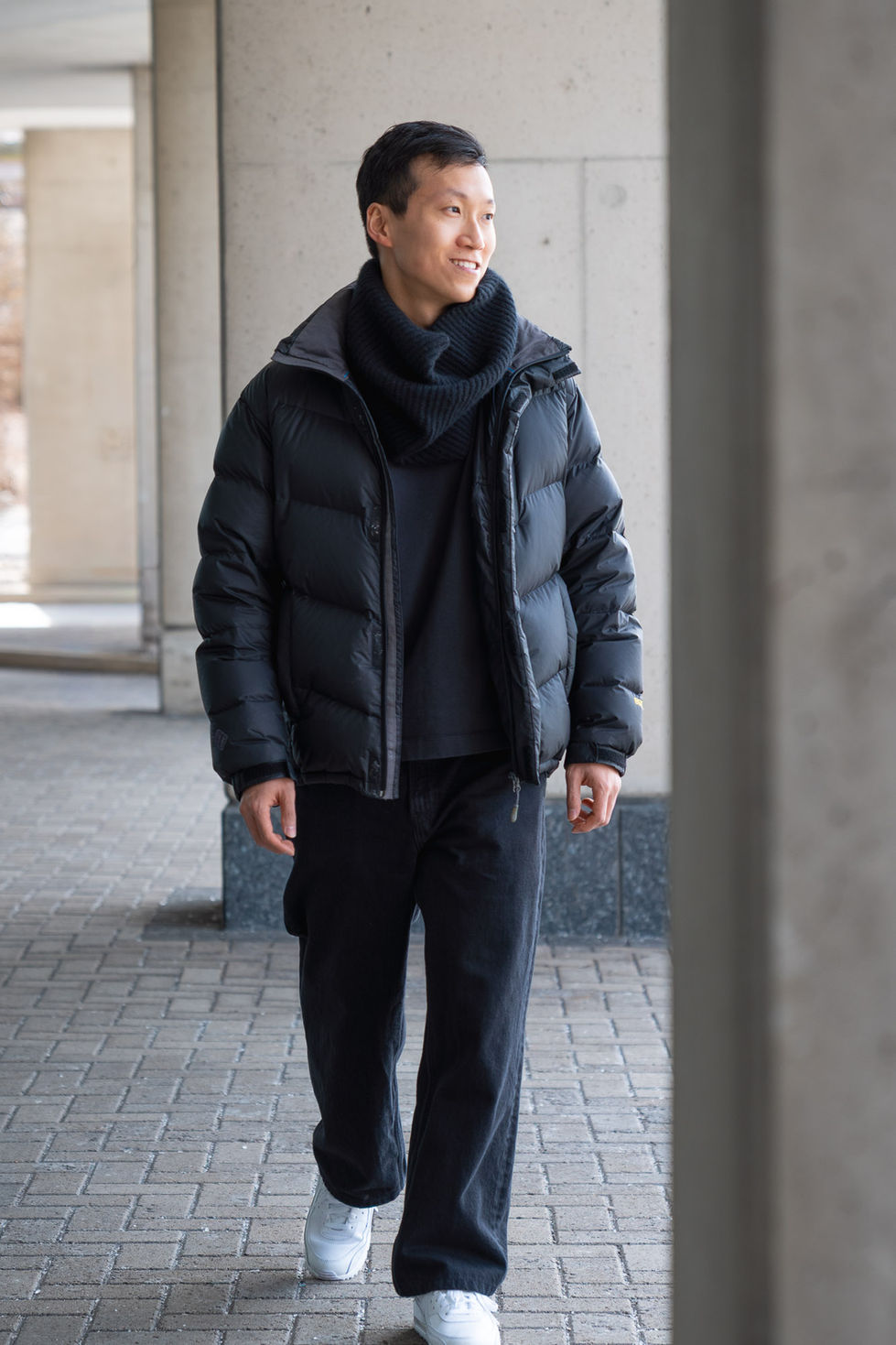 Editorial portrait of a man walking outdoors in a puffer jacket and scarf in Toronto