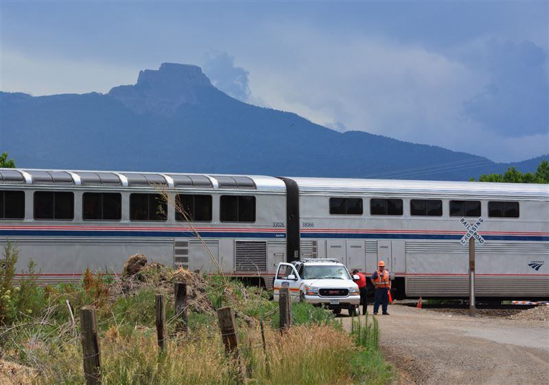 Workers from BNSF Railway and the Fisher's Peak Fire Department stand by an Amtrak train after it collided with a minivan at a crossing east of Trinidad, Colo., Monday, June 27, 2016. A 4-year-old girl was the only member of her family to survive after their minivan was hit by the Amtrak train at the crossing with a history of problems in southern Colorado, authorities said. (Eric John Monson/The Trinidad Chronicle News via AP) MANDATORY CREDIT (Eric John Monson)
