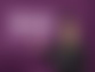 Woman in black called arin khuri points to screen displaying "IMLE Exam Dates 2026" in a purple lecture room. She smiles, creating an informative mood.