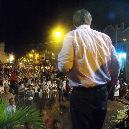 Pastor Chris Buscher preaching at night to a large crowd in a city square