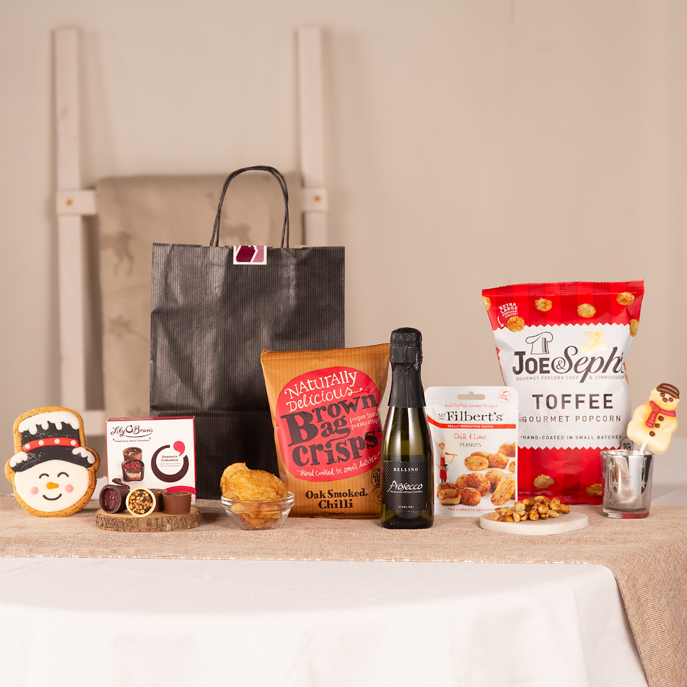 Festive gift selection with snacks and treats displayed next to a black jute gift bag
