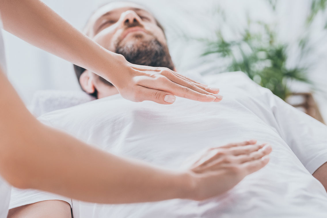 close-up view of bearded man receiving reiki healing session above stomach and chest.jpg
