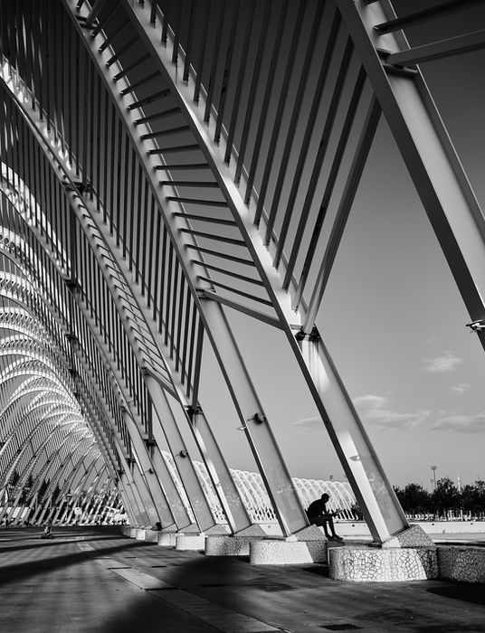 SIlhouette lisant un libre entre les structures métalliques du stade olympique à Athènes