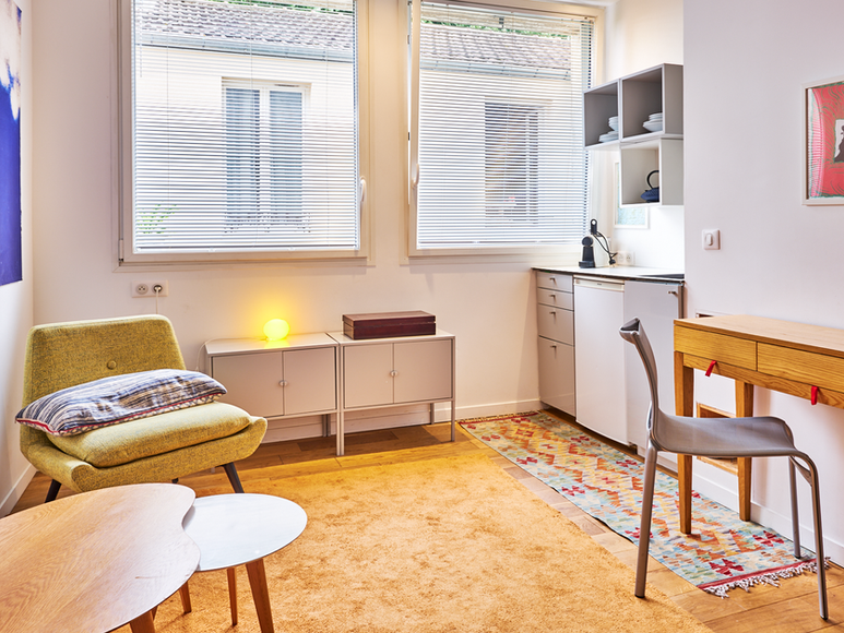 Pièce principale lumineuse d’un studio Airbnb à Paris avec espace repas et cuisine