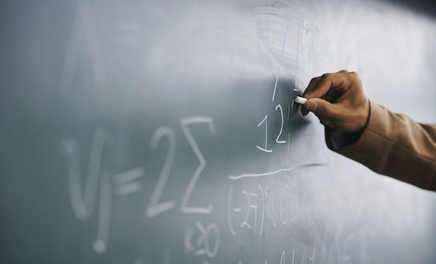 Teacher Writing a Formula on a Blackboar