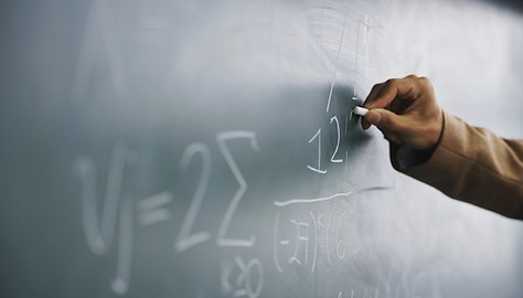 Teacher Writing a Formula on a Blackboar