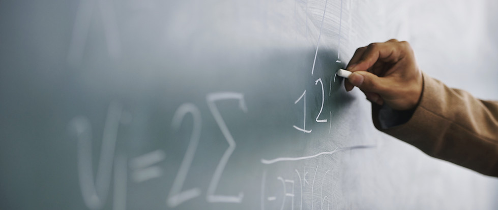 Teacher Writing a Formula on a Blackboar