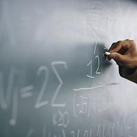 Teacher Writing a Formula on a Blackboar