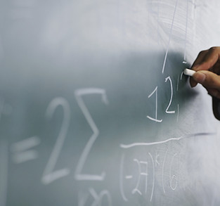 Teacher Writing a Formula on a Blackboar