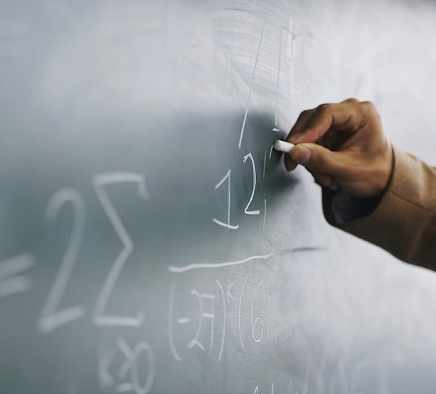 Teacher Writing a Formula on a Blackboard