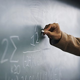 Teacher Writing a Formula on a Blackboar