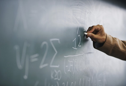 Teacher Writing a Formula on a Blackboar
