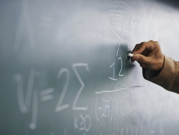 Teacher Writing a Formula on a Blackboar