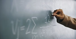 Teacher Writing a Formula on a Blackboard