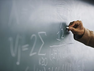 Teacher Writing a Formula on a Blackboard