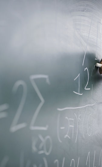 Teacher Writing a Formula on a Blackboard