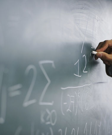 Teacher Writing a Formula on a Blackboard