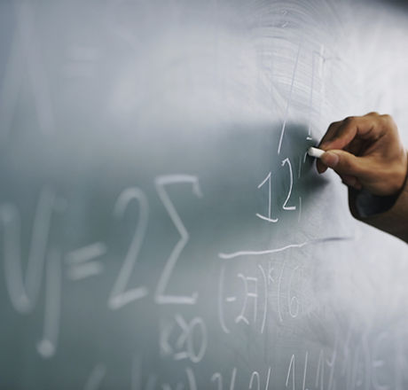 Teacher Writing a Formula on a Blackboard