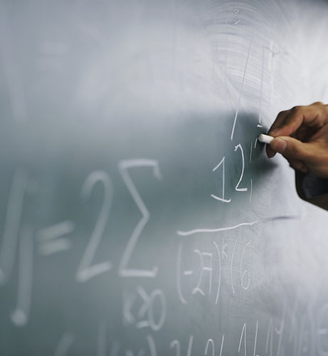 Teacher Writing a Formula on a Blackboard
