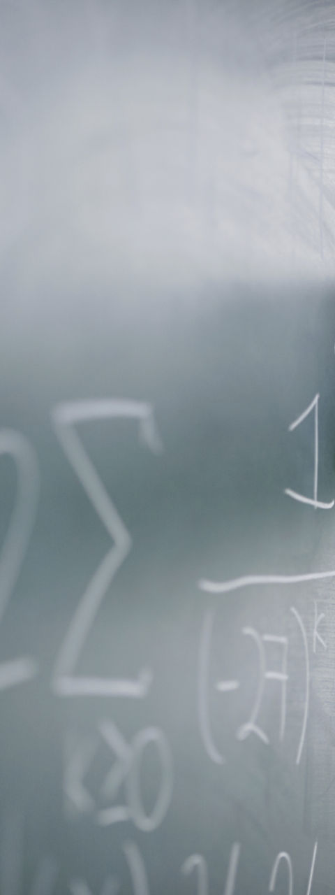 Teacher Writing a Formula on a Blackboard