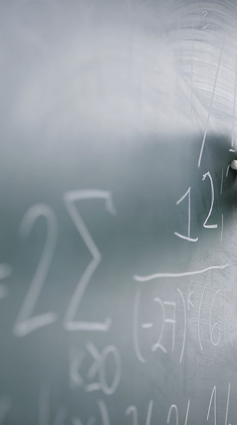 Teacher Writing a Formula on a Blackboard
