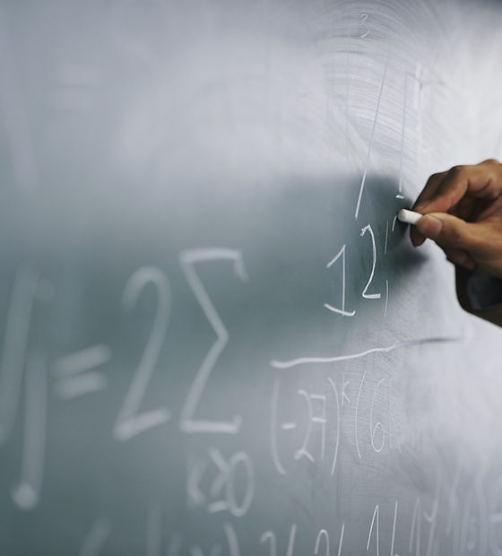 Teacher Writing a Formula on a Blackboard